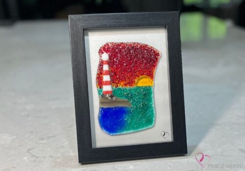 Work in fused glass representing a lighthouse under a blazing red sky, framed 5 x 7, Horizon de Percé-Verre collection.