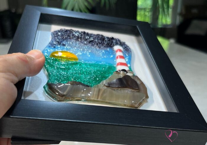 Lighthouse No. 3 - Horizon Collection. Fused glass with mauve sky and sunset. Lighthouse on rocks by the water. One-of-a-kind 5 x 7 frame.