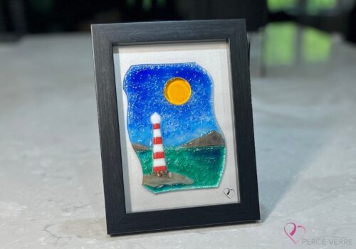Work in fused glass representing a lighthouse by the sea, under a blue sky. Water and sky in harmony. 5 x 7 frame, Horizon collection.