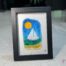 Voilier No. 5 Œuvre en verre fusionné représentant un voilier sur la mer, encadrée au format 5 x 7. Collection Cap sur les rêves, signée Percé-Verre.