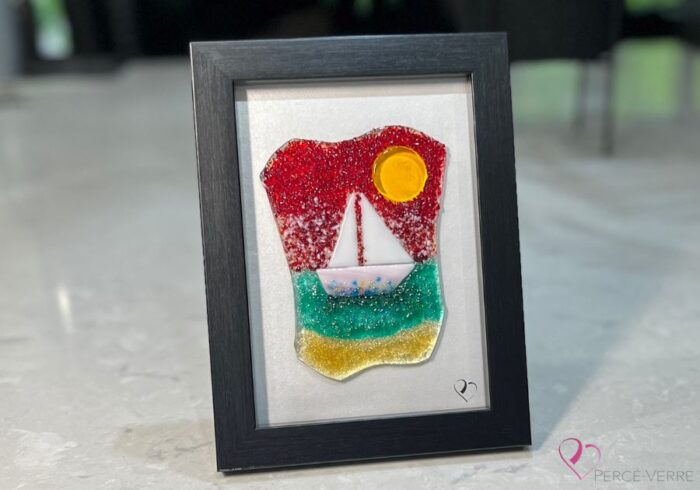 Voilier No. 7 Œuvre en verre fusionné représentant un voilier sur la mer, encadrée au format 5 x 7. Collection Cap sur les rêves, signée Percé-Verre.